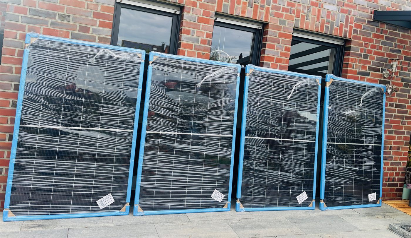 Vier eingeschweißte Solarmodule lehnen an einer Backsteinwand
